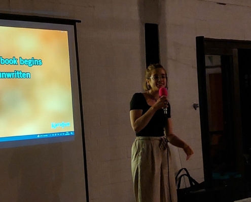 Frau singt Karaoke, im Hintergrund eine Leinwand mit Liedtext.